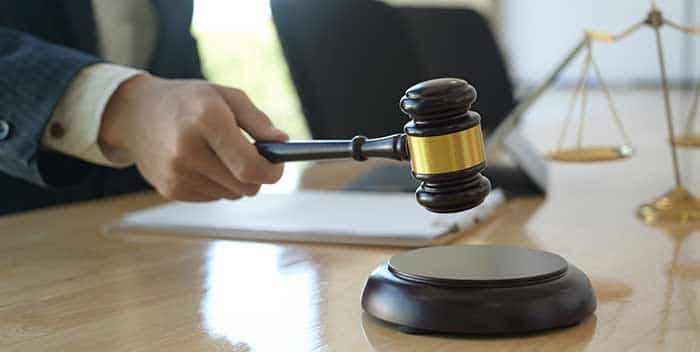 Un mazo de juez sobre un fajo de billetes en una mesa de oficina con vistas a un entorno de lujo, representando el caso del abogado de Marbella.